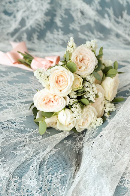 A beautifully arranged bridal bouquet featuring soft peach and cream roses, white lisianthus, and sprigs of white gypsophila, accented with round green eucalyptus leaves. The flowers are fresh, with d